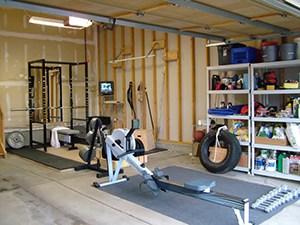 Cardio Packed Home Gym With A Tire And Power Rack. Shelves On The Side Keep All The Miscellaneous Stuff Out Of The Way,